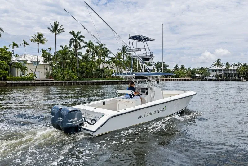 Slide: The Image of 1997 Venture 34 Center Console boat cruising on a scenic waterway with palm trees. - 13