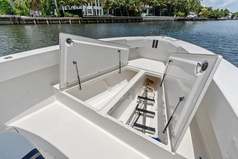 Slide: The Image of Open storage compartments on a 1997 Venture 34 Center Console boat by the water. - 23