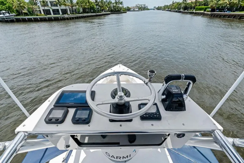 Slide: The Image of 1997 Venture 34 Center Console helm with steering wheel and navigation equipment on a calm waterway. - 40