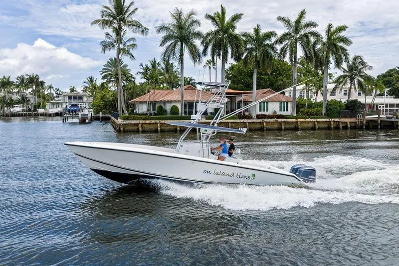Slide: The Image of 1997 Venture 34 Center Console boat cruising near palm-lined waterfront homes. - 8