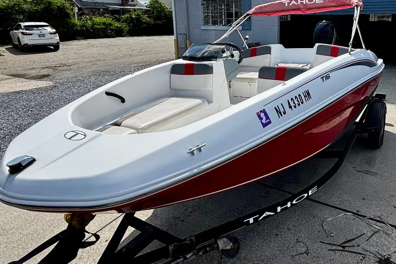 The Image of 2020 Tahoe T16 boat with red and white design on a trailer, parked outdoors. - 0