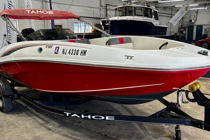 Slide: The Image of 2020 Tahoe T16 boat with red hull on trailer in indoor showroom. - 2