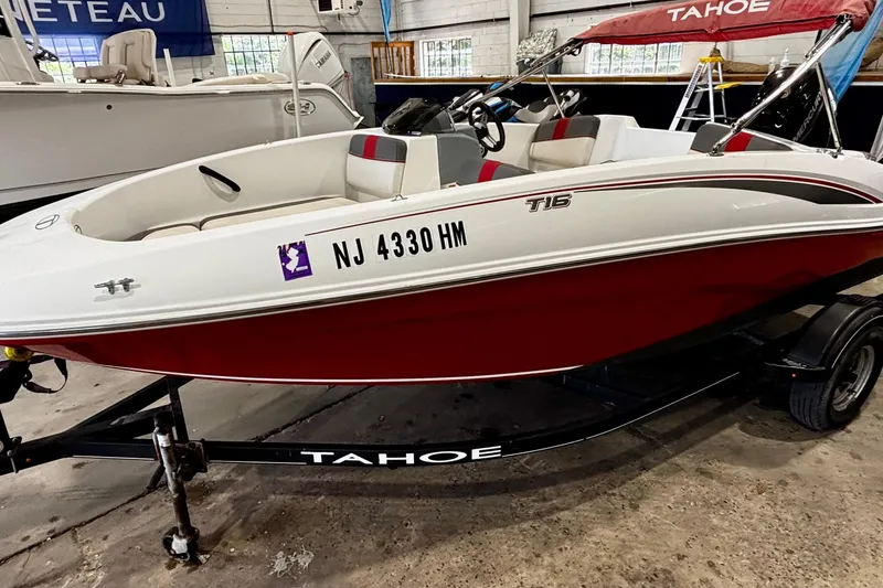 Slide: The Image of 2020 Tahoe T16 boat with red and white design on a trailer in a showroom. - 3