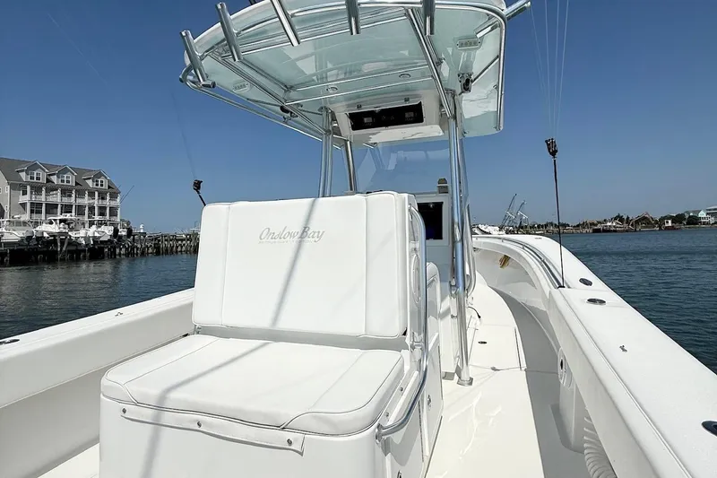 Slide: The Image of 2015 Onslow Bay boat with white seating, docked near waterfront buildings under clear blue sky. - 15