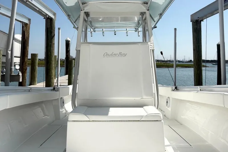 Slide: The Image of 2015 Onslow Bay boat interior with white seating, docked by the water. - 17