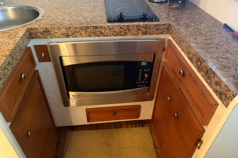 Slide: The Image of 1971 Chris-Craft 42 Commander kitchen with microwave, stovetop, and wooden cabinetry. - 19