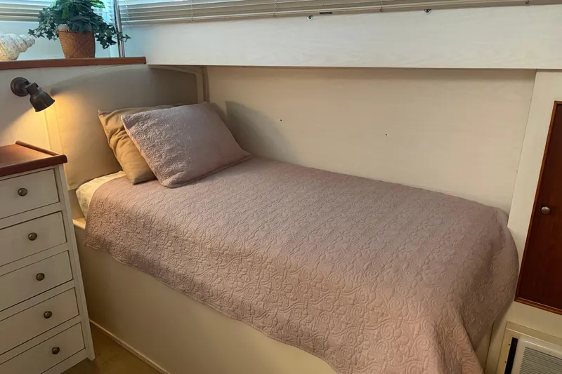 Slide: The Image of Cozy cabin bed in a 1971 Chris-Craft 42 Commander yacht, featuring elegant bedding and soft lighting. - 26