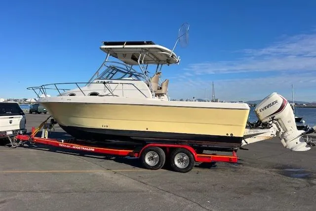 Slide: The Image of 1998 Pro-Line 2610 Walkaround boat on red trailer, parked near waterfront. - 24