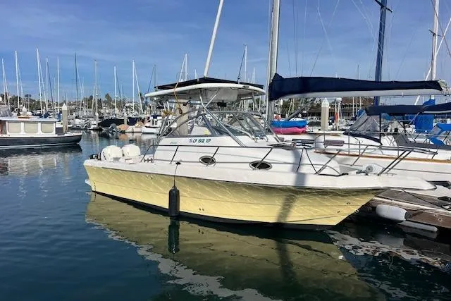 Slide: The Image of 1998 Pro-Line 2610 Walkaround boat docked in a marina with clear skies. - 16