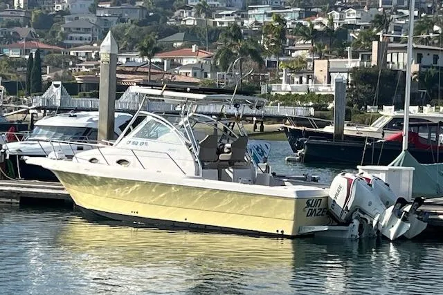 Slide: The Image of 1998 Pro-Line 2610 Walkaround boat docked in a marina with scenic background. - 8