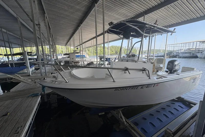 Slide: The Image of 2007 Edgewater 188CC boat docked under a covered marina, featuring a sleek white design. - 2