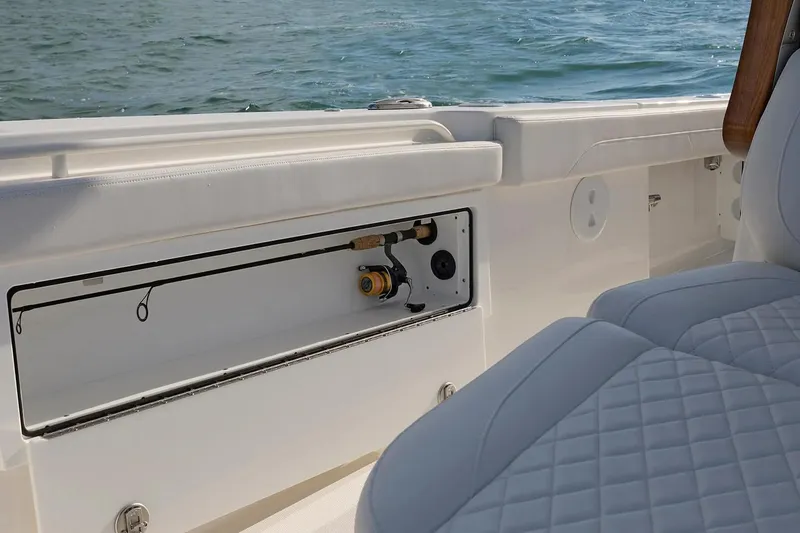 Slide: The Image of Fishing rod storage on 2027 Regulator 30XO boat, featuring quilted seating and ocean backdrop. - 12