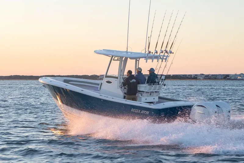 Slide: The Image of 2027 Regulator 25 boat cruising on water at sunset with fishing rods. - 11