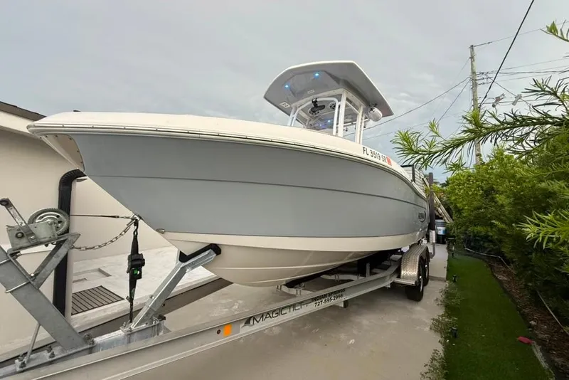 Slide: The Image of 2020 Robalo R222 Explorer boat on trailer, parked outdoors near greenery. - 20