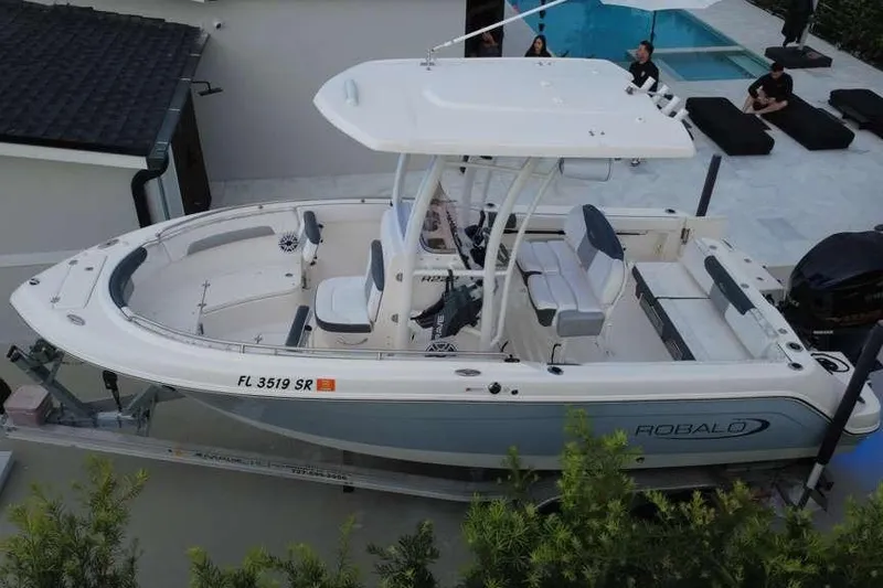 Slide: The Image of 2020 Robalo R222 Explorer boat on trailer, parked near a poolside patio. - 3