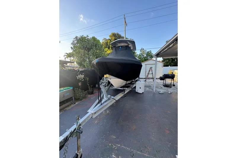 Slide: The Image of 2021 Robalo R222 Center Console boat covered on a trailer in a driveway. - 33