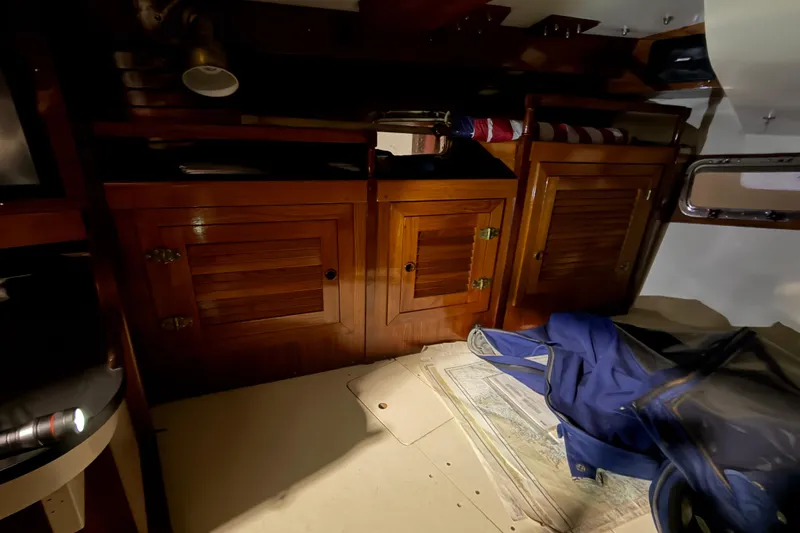 Slide: The Image of 1978 CSY 44 Center Cockpit interior with wooden cabinets and nautical charts. - 12
