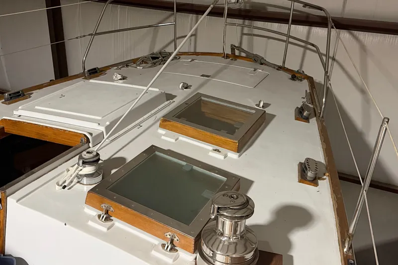 Slide: The Image of 1978 CSY 44 Center Cockpit sailboat deck with hatches and winches in a storage facility. - 6
