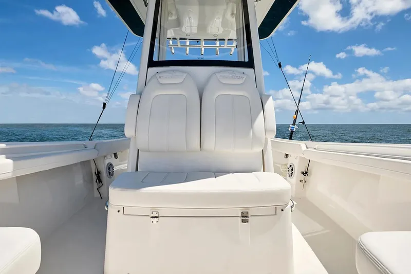 Slide: The Image of 2027 Regulator 23 boat interior with white seating, ocean view, and fishing rods. - 18