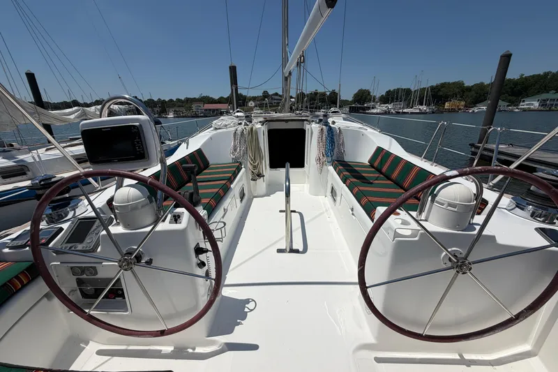 Slide: The Image of 2003 Beneteau Oceanis 473 sailboat cockpit with dual steering wheels and striped seating. - 4