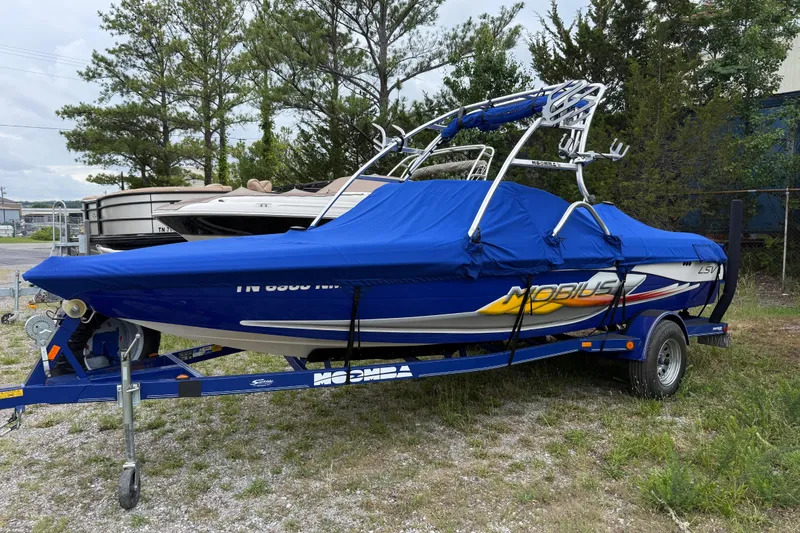 Slide: The Image of 2002 Moomba Mobius LSV boat with blue cover on trailer, parked outdoors. - 3