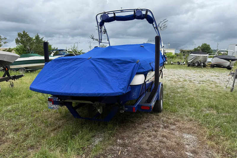 Slide: The Image of 2002 Moomba Mobius LSV boat covered in blue tarp, parked outdoors on grass. - 8