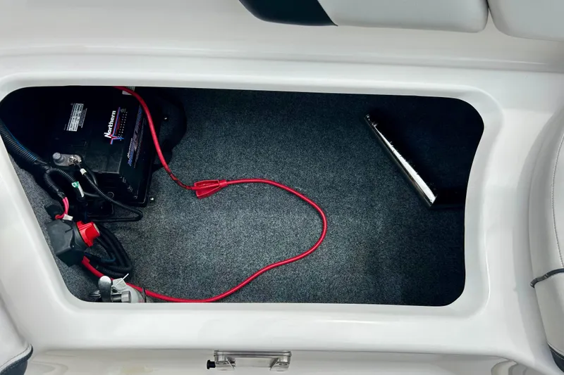 Slide: The Image of 2015 Yamaha AR210 boat battery compartment with wiring and carpeted interior. - 44