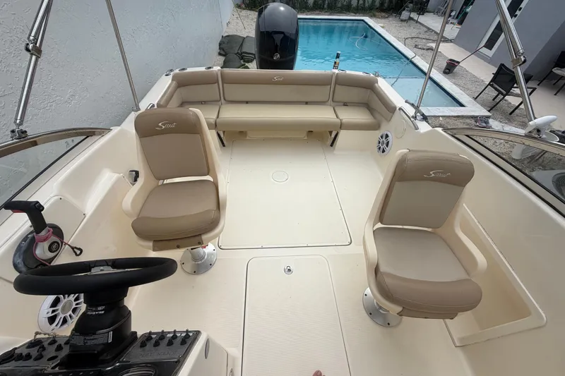 Slide: The Image of 2023 Scout 210 Dorado boat interior with beige seating, near a swimming pool. - 9