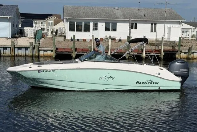 The Image of 2023 NauticStar 223 DC boat on water near docked houses. - 0