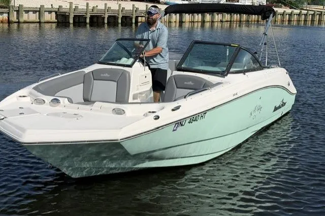 Slide: The Image of 2023 NauticStar 223 DC boat on water, man steering, sunny day. - 1