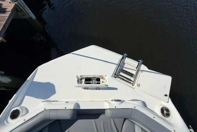 Slide: The Image of 2023 NauticStar 223 DC boat bow with seating and ladder, docked on calm water. - 10