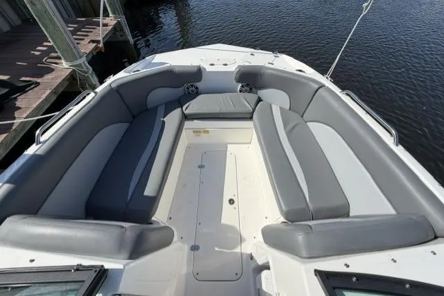 Slide: The Image of 2023 NauticStar 223 DC boat interior with gray seating, docked by water. - 11