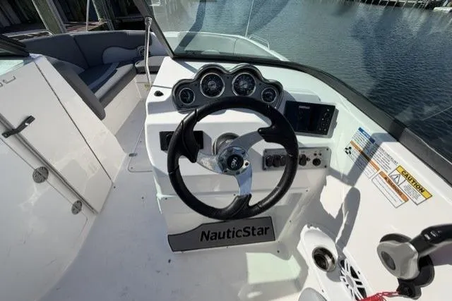 Slide: The Image of 2023 NauticStar 223 DC boat dashboard with steering wheel and control panel. - 14