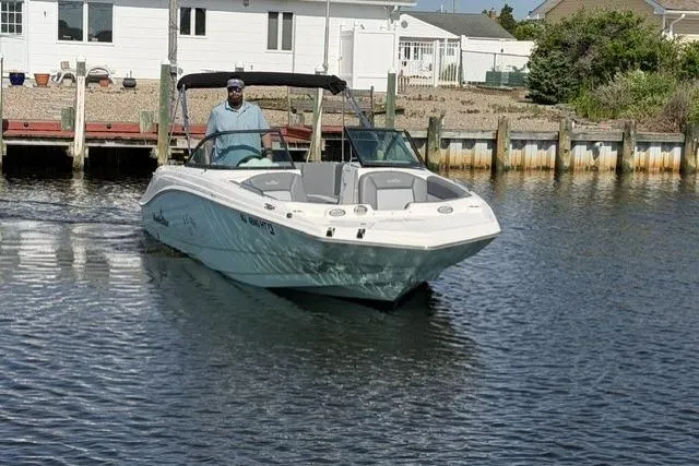 Slide: The Image of 2023 NauticStar 223 DC boat cruising near a dockside house. - 2