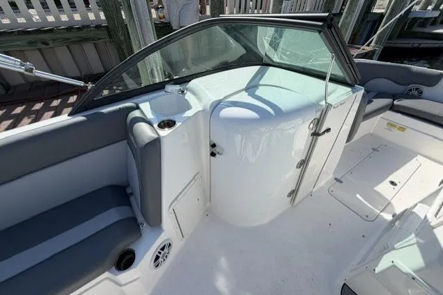 Slide: The Image of 2023 NauticStar 223 DC boat interior with seating and windshield, docked at marina. - 21