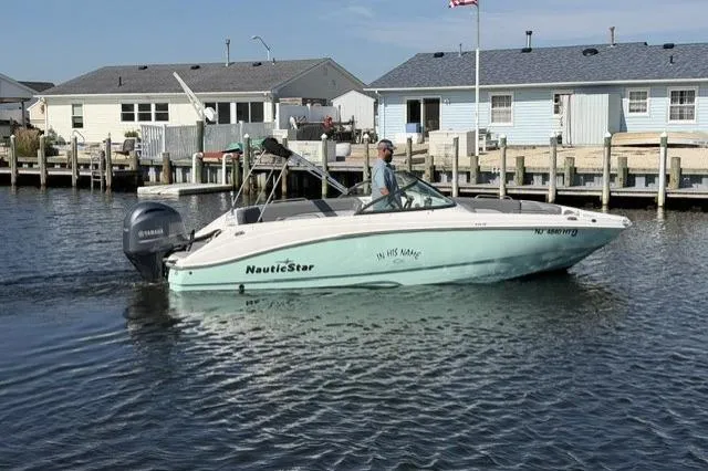 Slide: The Image of 2023 NauticStar 223 DC boat cruising near waterfront homes. - 3