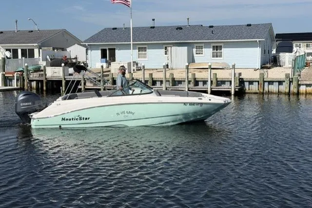 Slide: The Image of 2023 NauticStar 223 DC boat cruising near docks with houses in the background. - 5