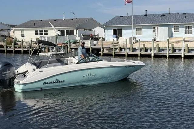 Slide: The Image of 2023 NauticStar 223 DC boat cruising near waterfront homes. - 6