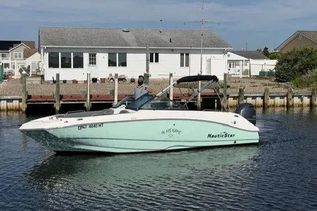Slide: The Image of 2023 NauticStar 223 DC boat cruising near a dockside house on a sunny day. - 7