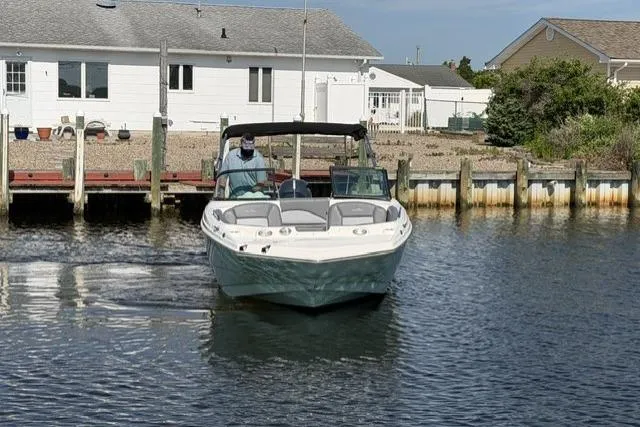 Slide: The Image of 2023 NauticStar 223 DC boat cruising near a dockside house. - 8