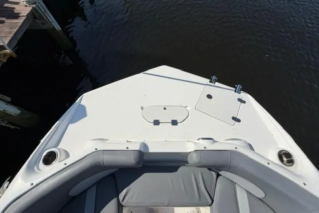Slide: The Image of 2023 NauticStar 223 DC boat bow with seating, docked by the water. - 9