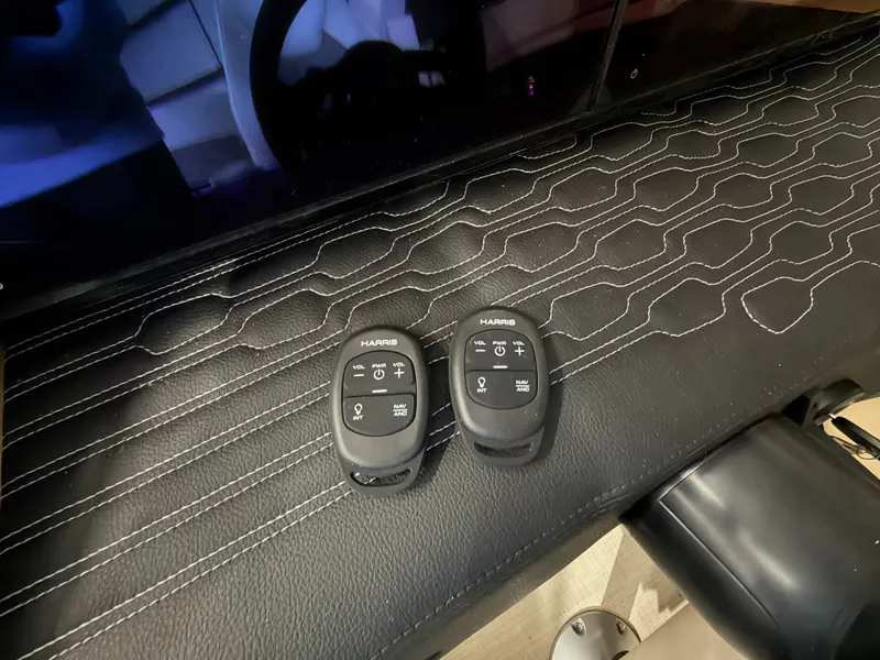 Slide: The Image of Two black remote controls on a textured surface inside the Harris 250CRW boat. - 46