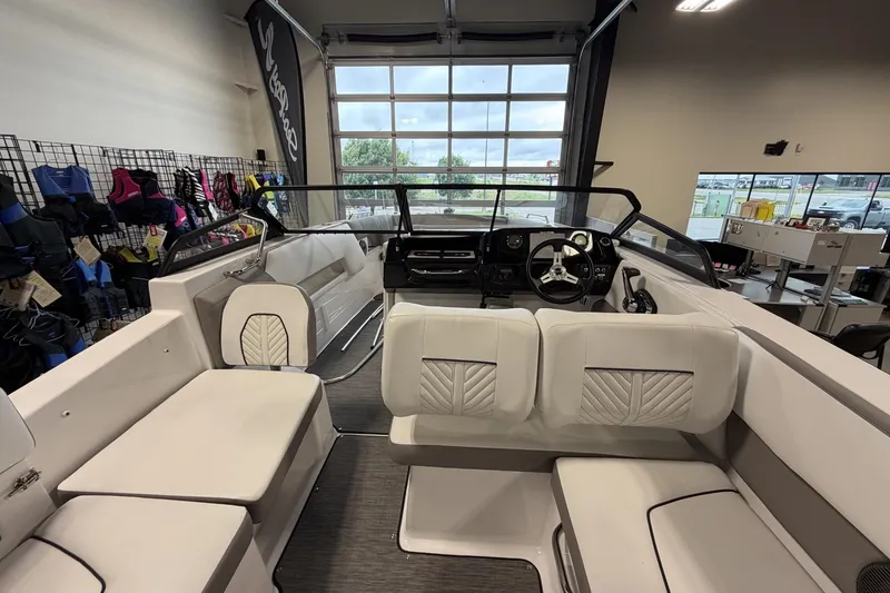 Slide: The Image of 2024 Glastron GTD 240 boat interior with white seating and modern dashboard in showroom. - 17