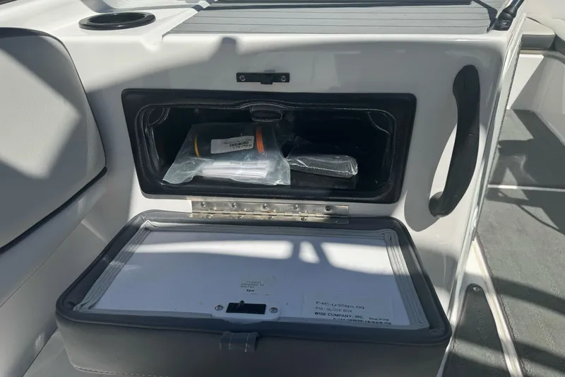 Slide: The Image of Storage compartment in a 2022 Yamaha AR190 boat, featuring safety equipment and documents. - 32
