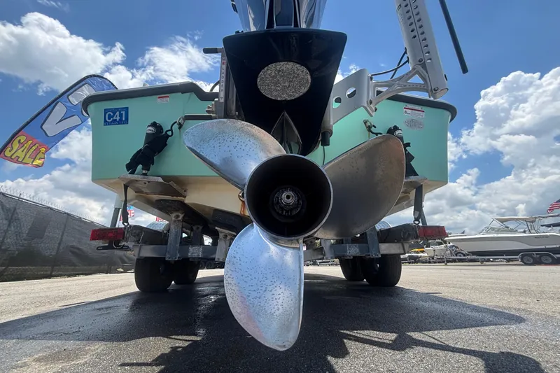 Slide: The Image of 2014 Mako 21 LTS boat on trailer, showcasing propeller and hull, under a sunny sky. - 5