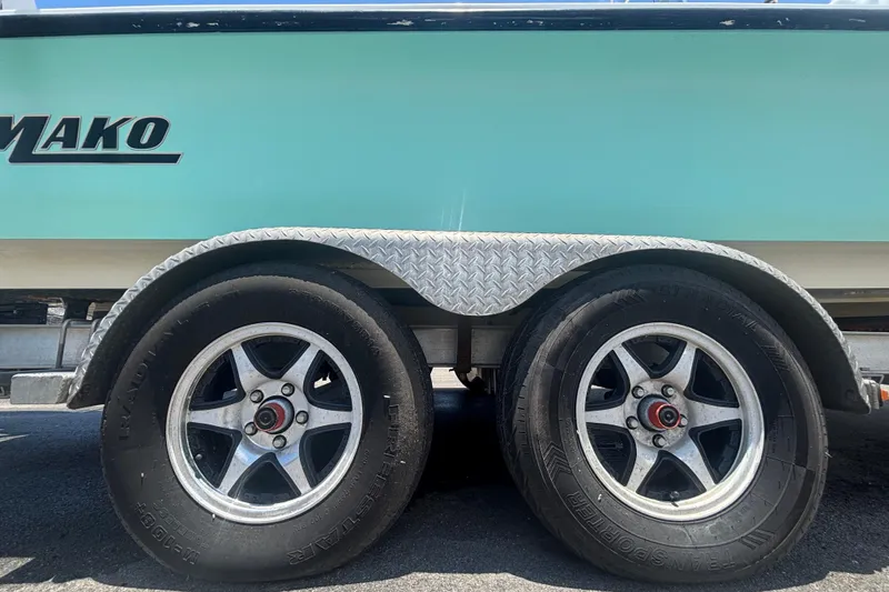 Slide: The Image of Trailer wheels of a 2014 Mako 21 LTS boat with teal hull. - 51