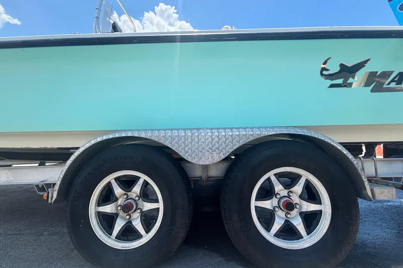 Slide: The Image of 2014 Mako 21 LTS boat on trailer with dual wheels, blue sky background. - 52