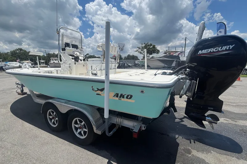 Slide: The Image of 2014 Mako 21 LTS boat with Mercury engine on a trailer under cloudy sky. - 9
