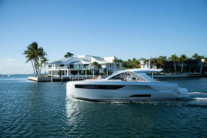 Slide: The Image of 2027 Jeanneau DB/43 OB yacht cruising near waterfront homes and palm trees. - 2