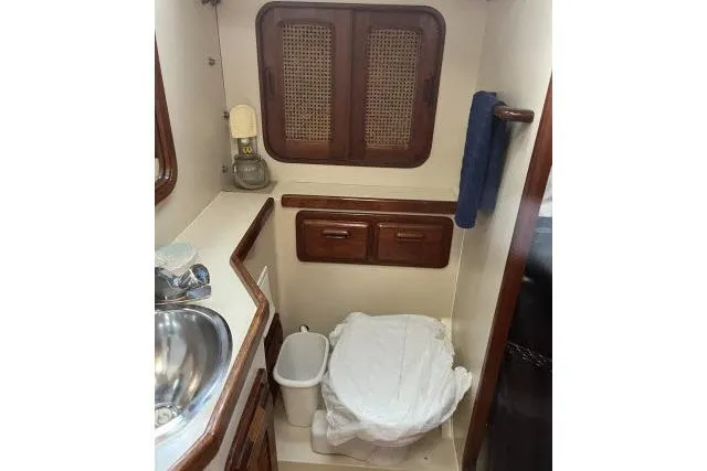 Slide: The Image of 1985 Islander Peterson 40 yacht bathroom with sink, toilet, and wooden cabinets. - 19